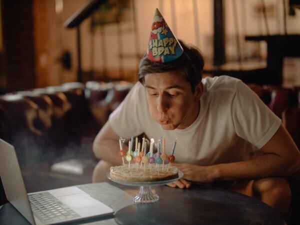 man in white crew neck t shirt sitting by the table with cake